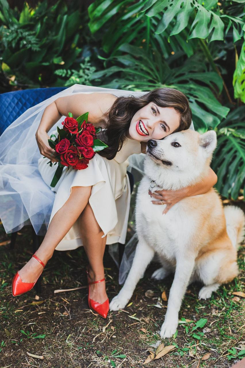 Joyful bride with red roses bouquet and beloved dog