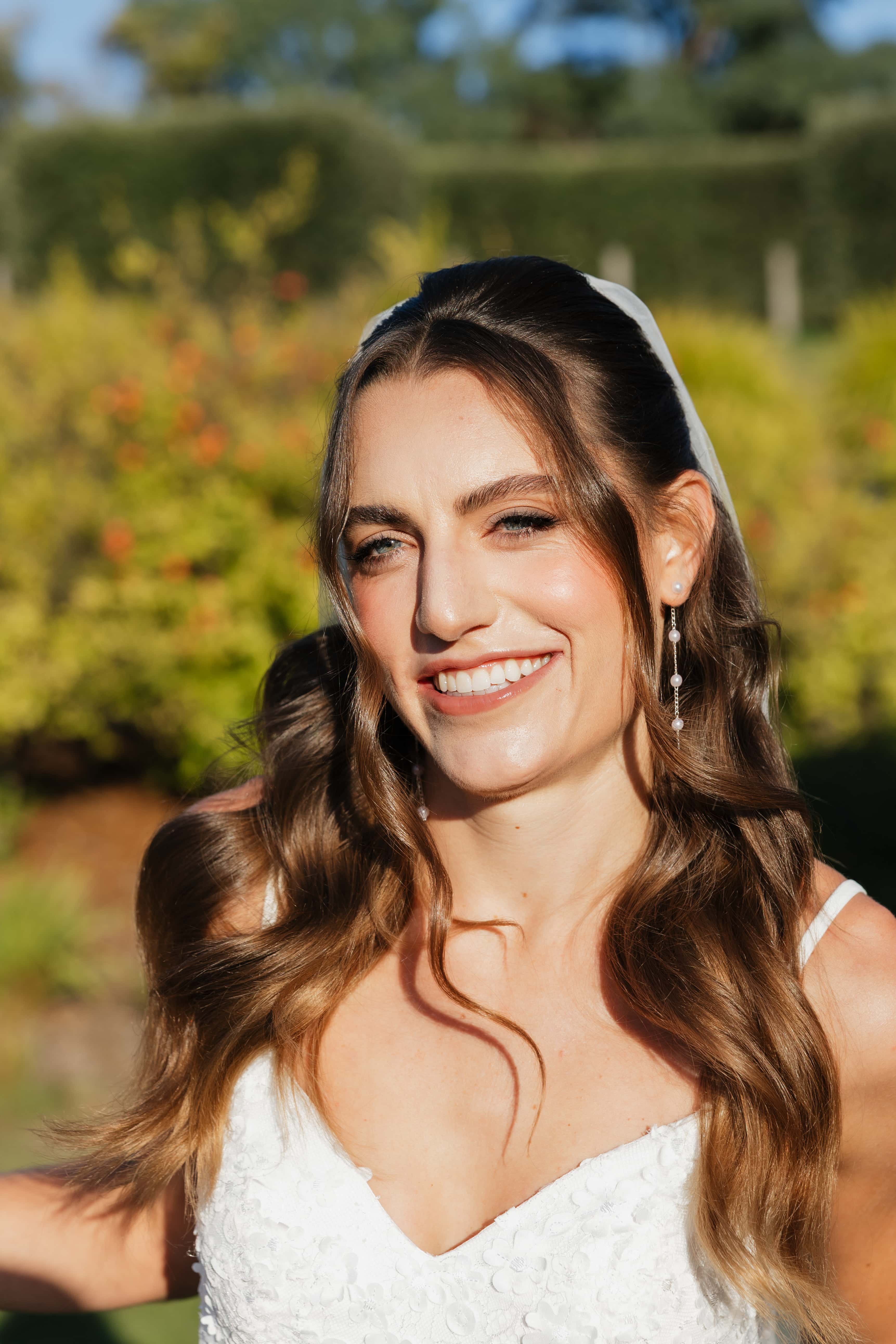 Brunette bride with veil in sunlit garden