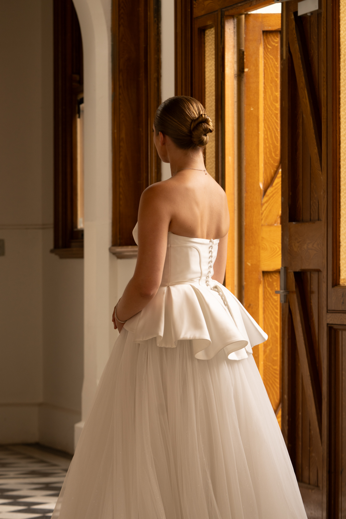 Bride with sleek low bun and peplum gown from behind