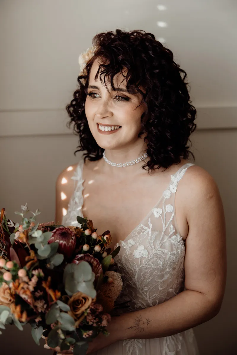 Bride with curly hair and autumn bouquet, soft window light